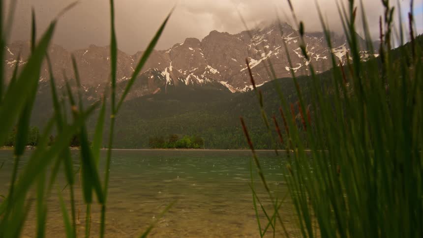 Landscape of a greenish lake surrounded by mountain ranges on a cloudy day