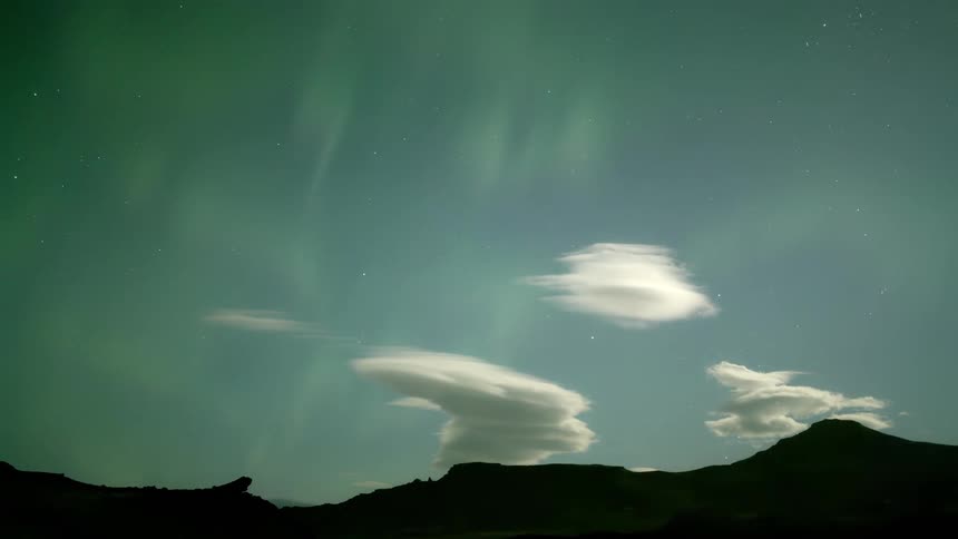 Timelapse of the sky with aurora borealis and silhouette of mountains in the background