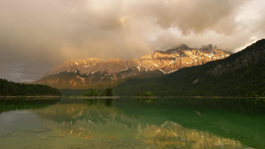 A lake sits in front of mountains covered in forests