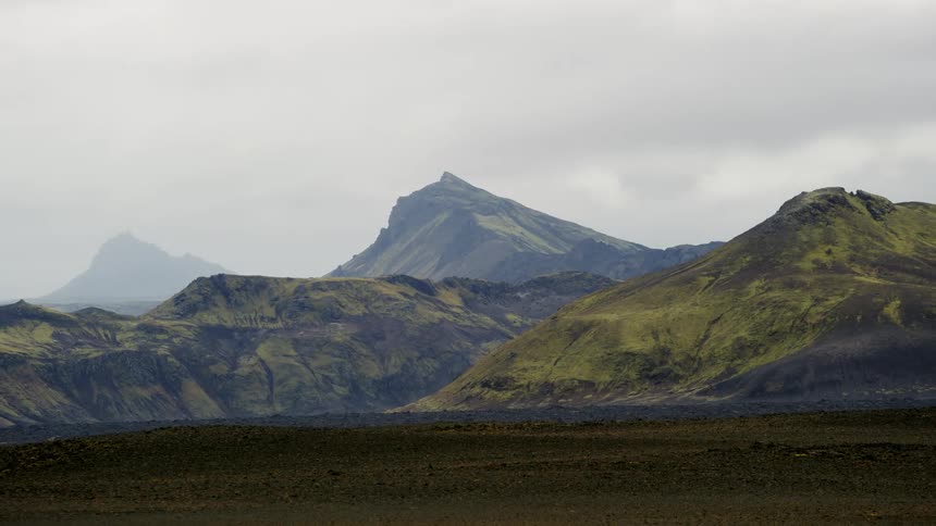 Green mountain peaks under cloudy sky