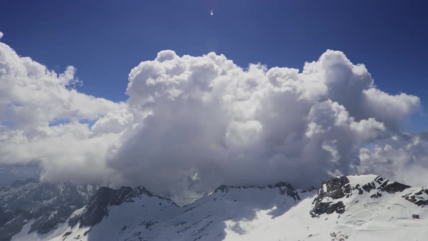 Landscape of mountains covered by snow at cloud level in a blue sky
