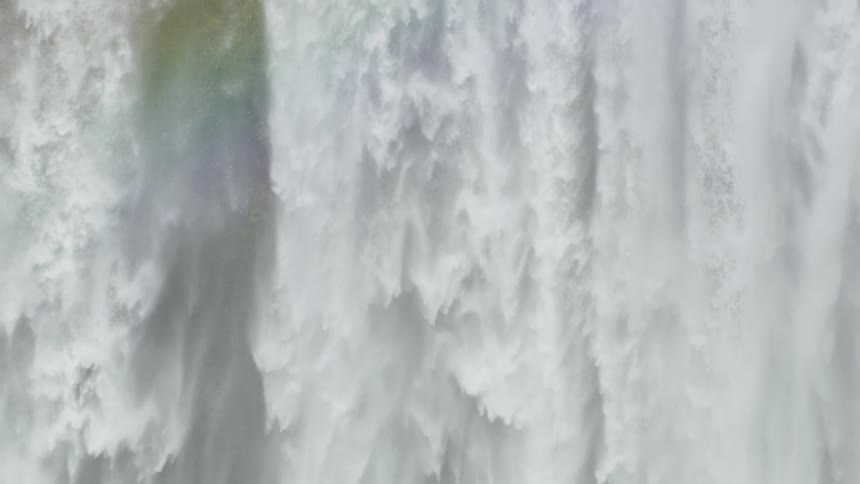 A rainbow in front of a waterfall flowing down