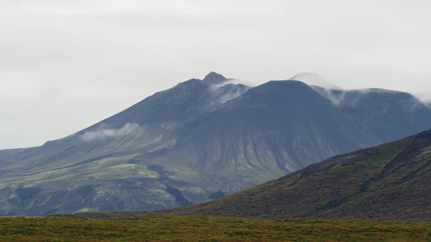 Panorama of a mountain range with vegetation and clouds passing on a cloudy day