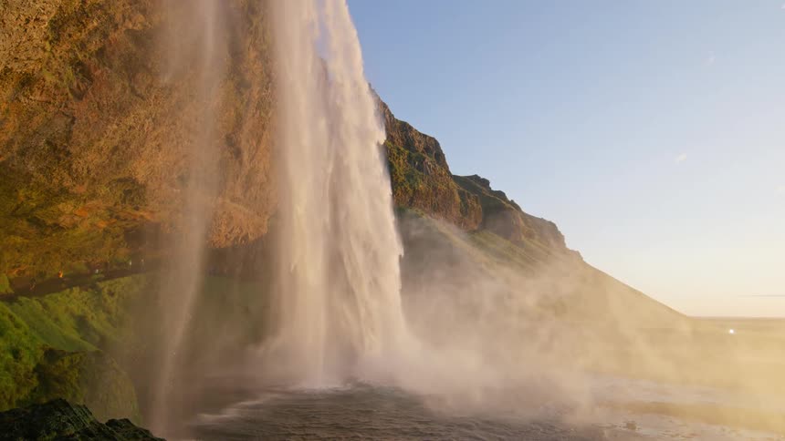 A serene scene of a large waterfall and a lake under a clear sky