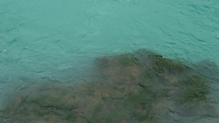 View down from a rock within a turquoise water with mosses