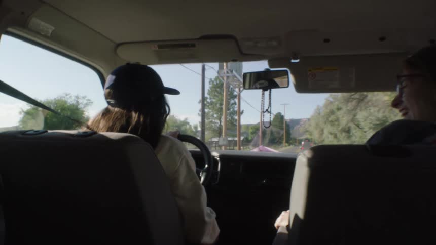 Female friends laugh together during road trip through rural countryside
