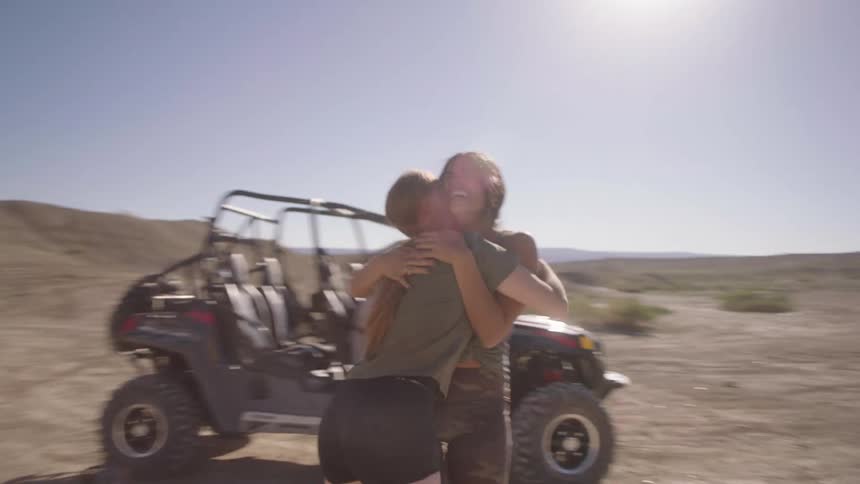 Two women running up and hugging each other outdoors