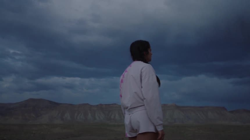 Woman in the midst of a canyon area on a day with a black sky