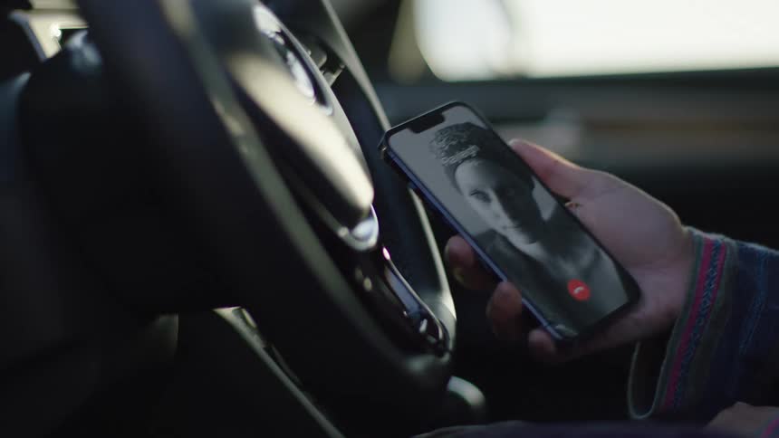 Female driver sitting in car answers phone call on smartphone