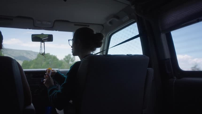 Woman taking medicine from a tube in the front passenger seat of a car