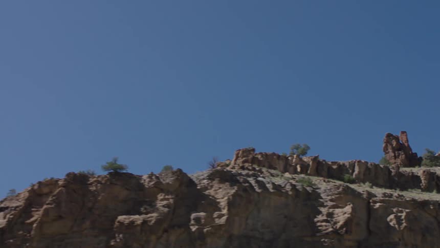 View of a rocky wall of a mountain with blue sky and no clouds