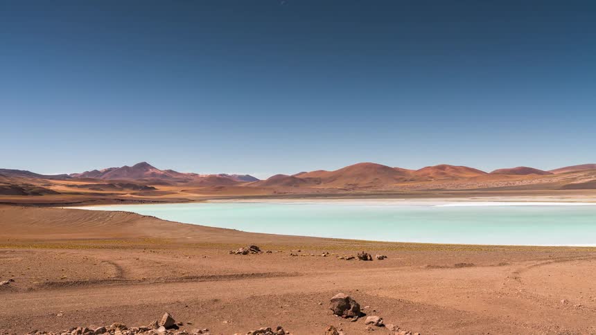 Light blue lake surrounded by barren hill terrain