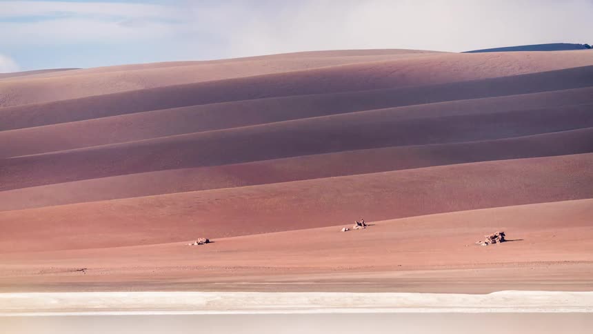 Time lapse clouds cast shadows on desert hill