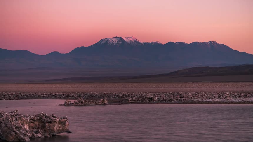 Landscape of a lake in front of mountain ranges with the day in dusk timelapse