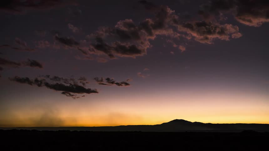 Clouds move over a wide open area with a mountain in the distance