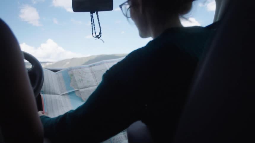 Two women argue over a map in a car