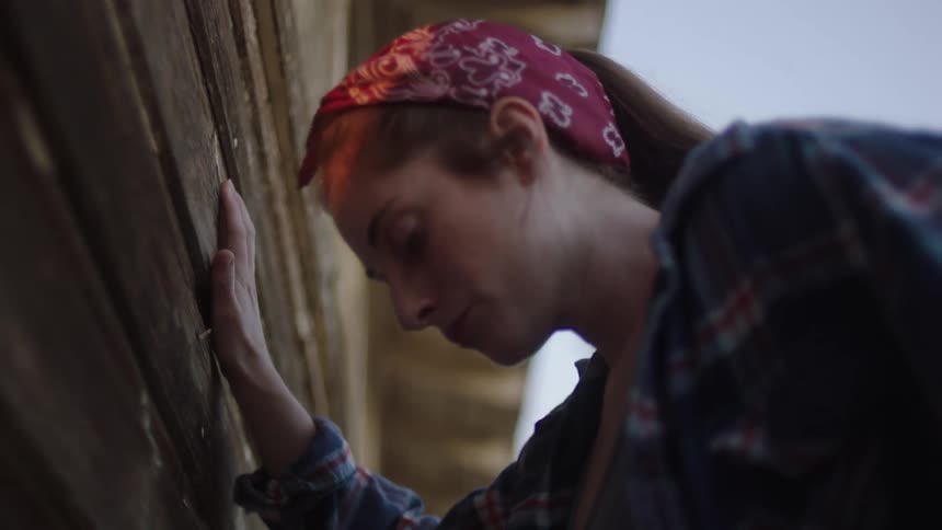 A woman with a bandana in her hair puts her hand on the wall and feels like vomiting