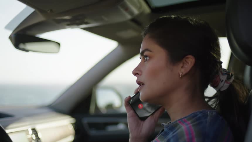 Portraits of a woman inside the car answering a phone call
