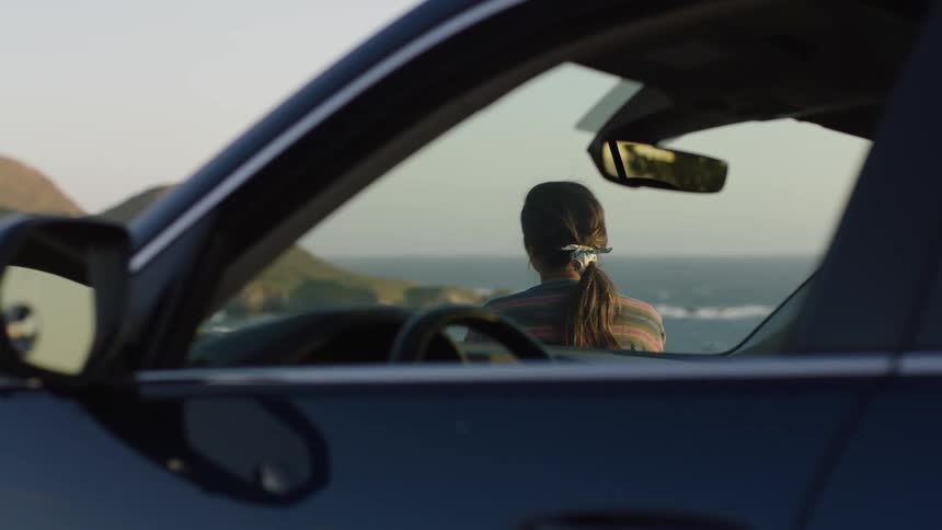 A woman getting out of the car to watch the sea