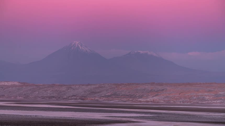 A volcanic mountain with snow at the peak of the desert