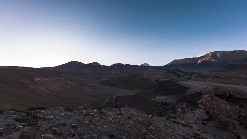 The sun rises over a mountain range and canyon