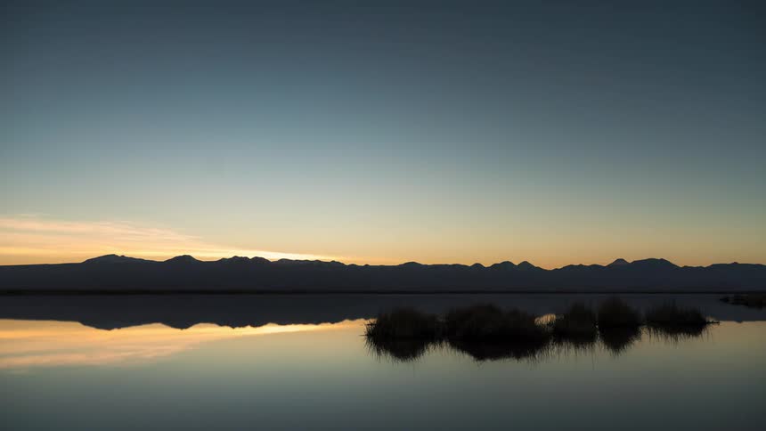 Night turns to day on a lake with the sky reflected in the water
