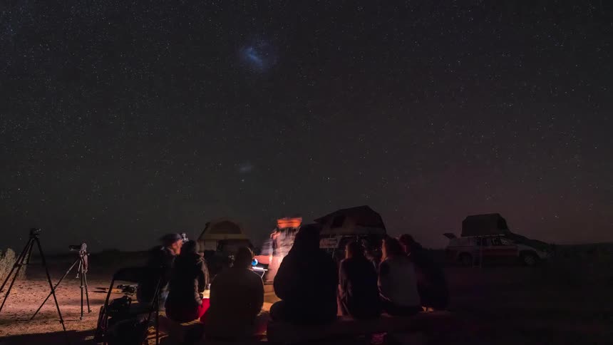Group of people in a natural outdoor setting organizing and transitioning from day to night in timelapse