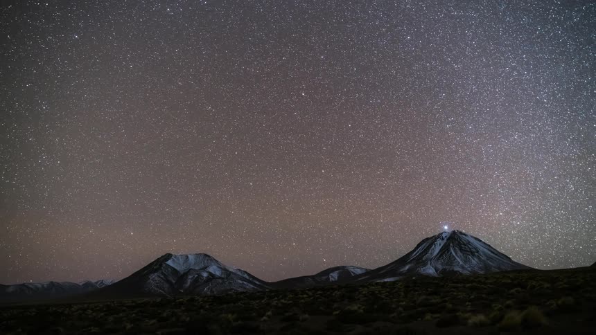A region with two mountains and the sky is getting dark and many stars appear and then it becomes morning