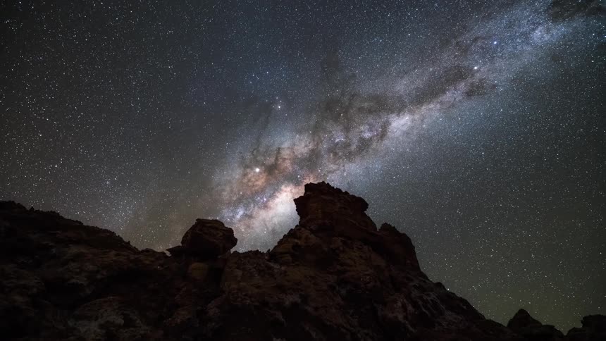 A starry sky and a galaxy appearing in a region with mountains