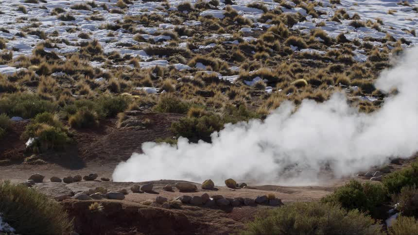 White smoke coming out of the ground in an area with some rocks on the ground