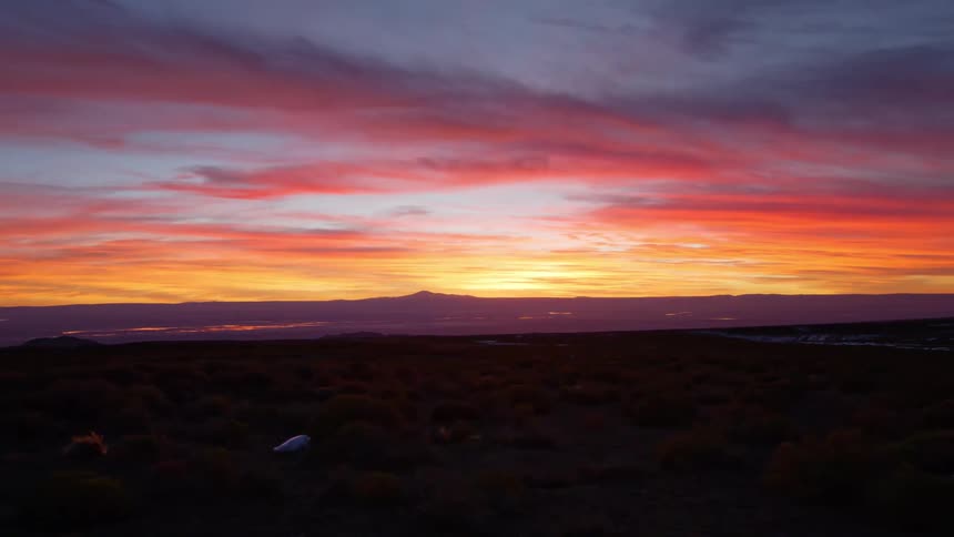 A desert region in the morning has lost the sun is rising and the sky is orange