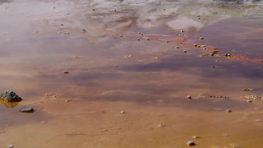 A puddle of water on the ground and smoke hovering over you leaving a shadow in the water