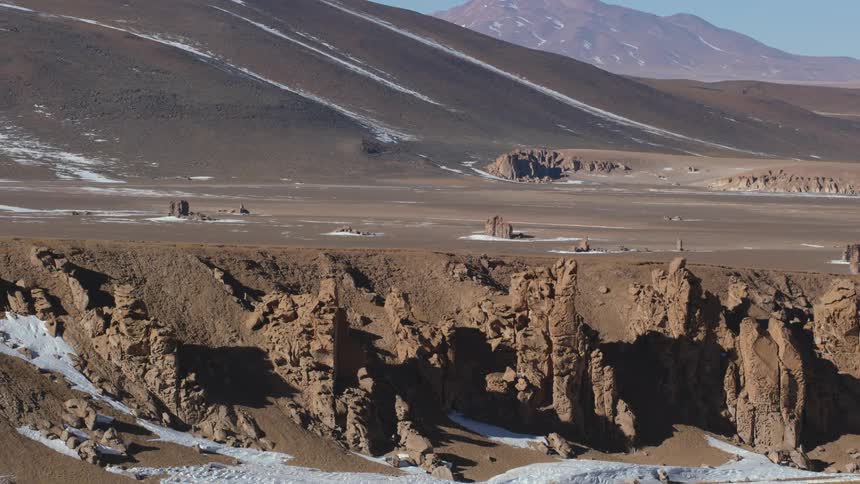 Snow melts in brown desert during sunny day