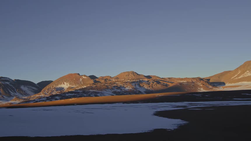 A region with some mountains and snow on the ground while sunlight is illuminating the mountains