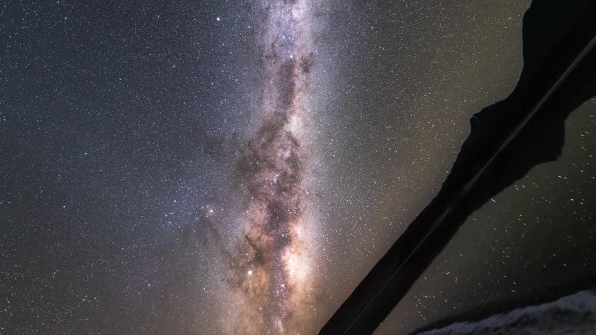 Reflective lake with surrounding mountains silhouette in a nebula sky in timelapse