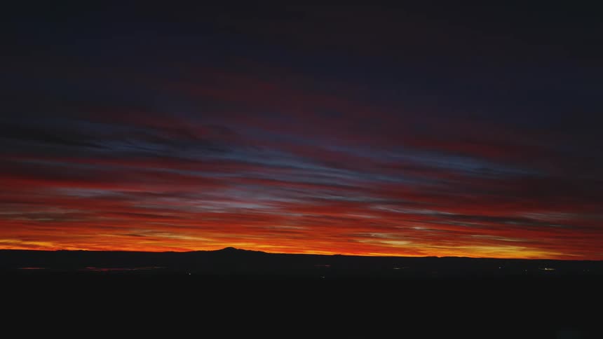 A desert region where the sky is orange and it is getting dark