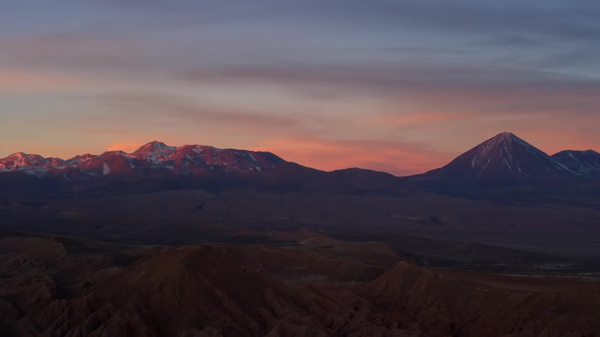 A low sun in the sky casts shadows over a mountain range