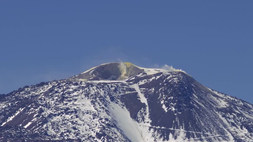 Smoke rises out of a snow covered volcano