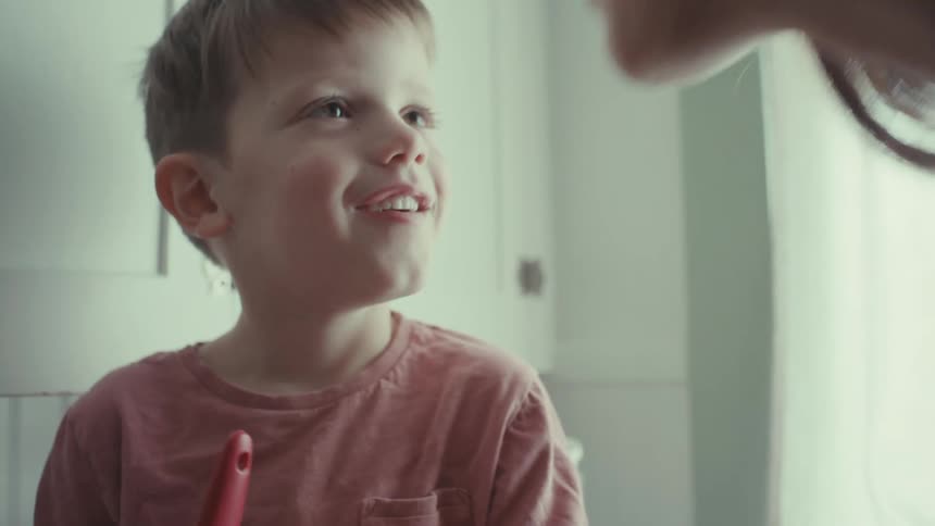 Mother kisses son as they cook together in kitchen