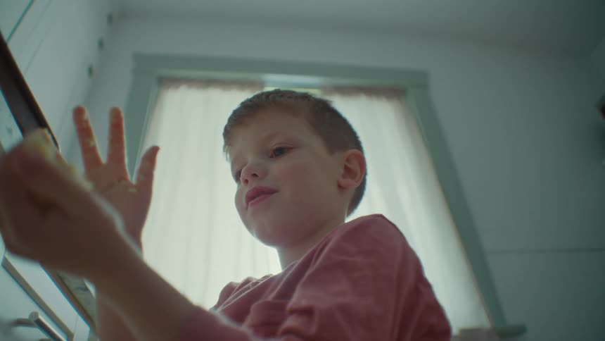 Close up of a boy helping to knead dough in the kitchen