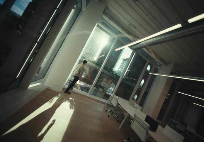 Man with a white shirt and black pants looks out the office windows in the office