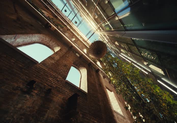 An interior of a building with ancient architecture and next to it a modern wall with mirrored glass
