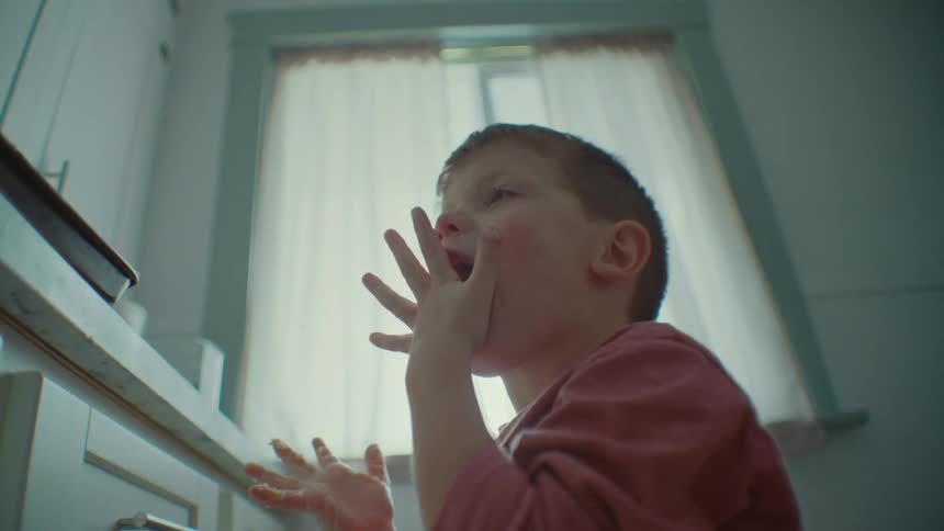Portrait of a young little boy licking his fingers