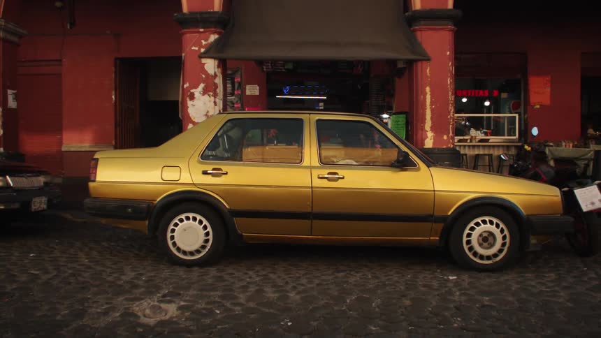 A gold car sits in front of a building