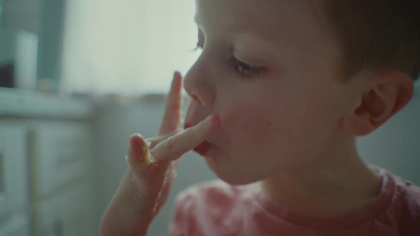 Portrait of a child licking their fingers