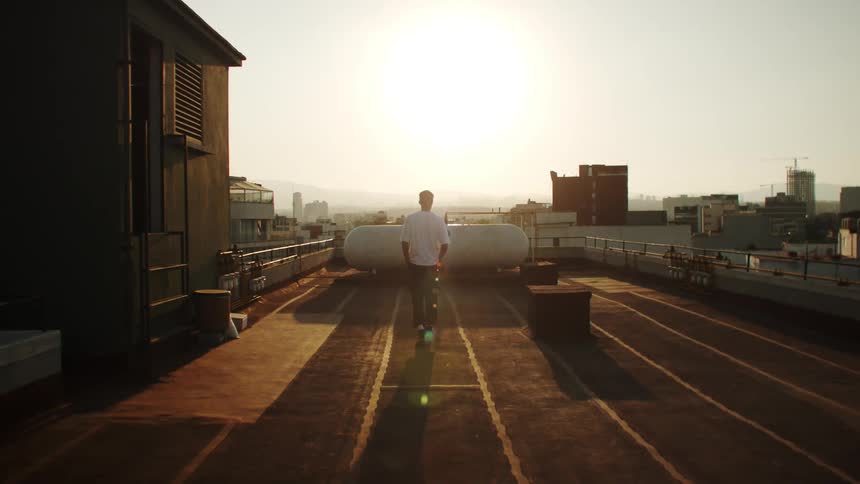 A person on a rooftop admires the sunset and the city view