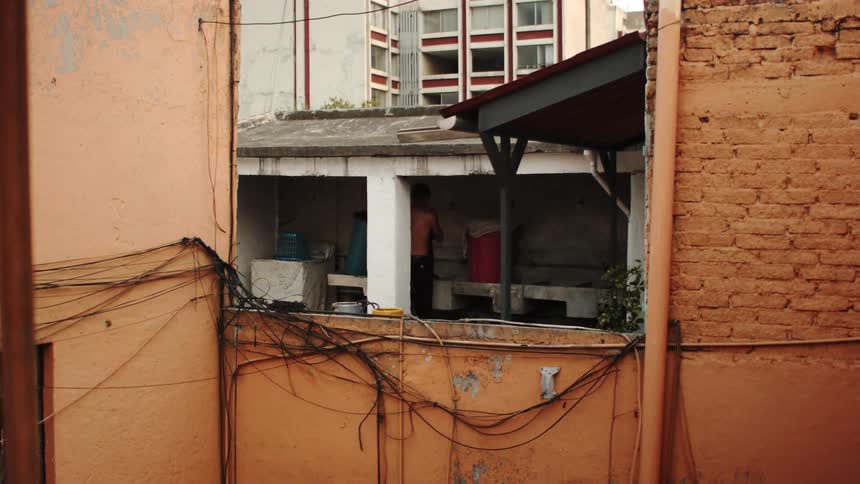 A person in the balcony of a building with aged walls in the city