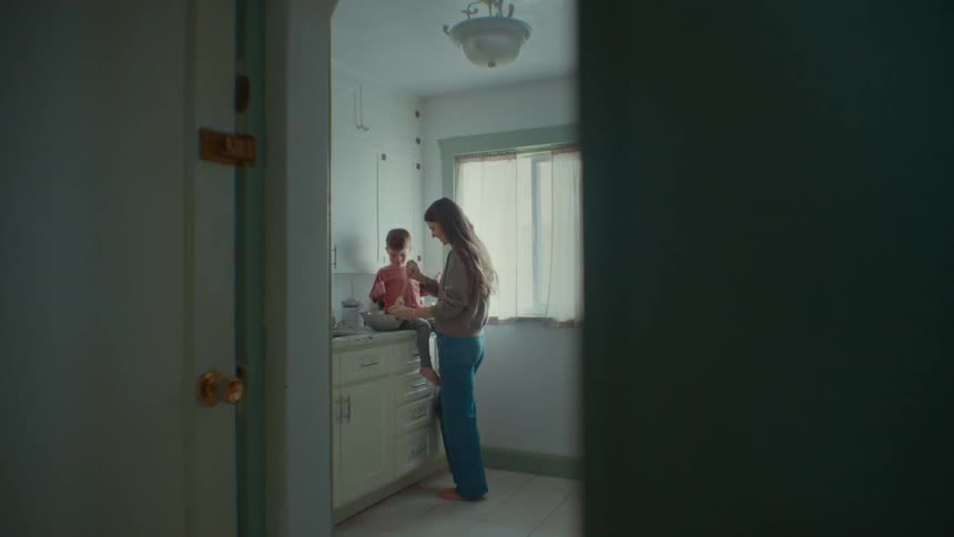 A mother and son prepare and taste food in a kitchen