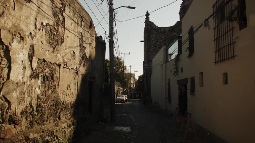 A narrow alleyway between an old wall and buildings