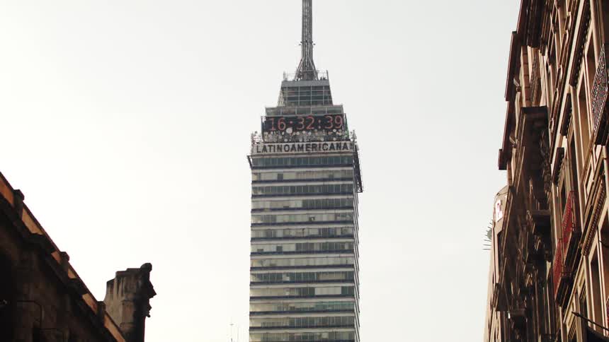 A skyscraper with a clock towers over a city
